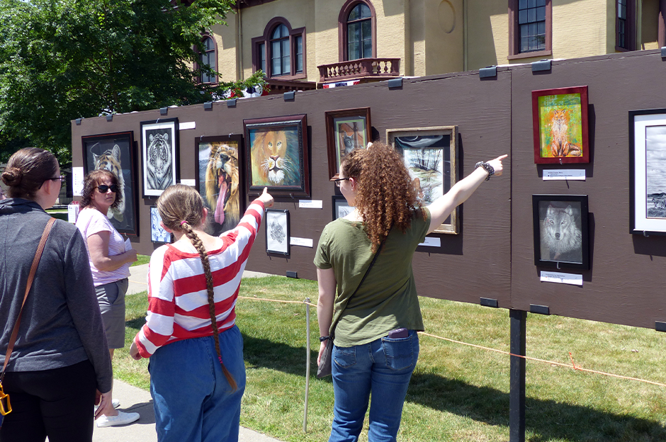 people pointing at fence line of artwork from arts festival from 2021