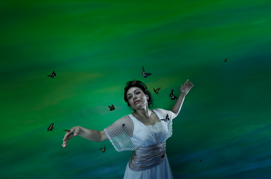 woman in white standing with butterflies surrounding them in front of green background