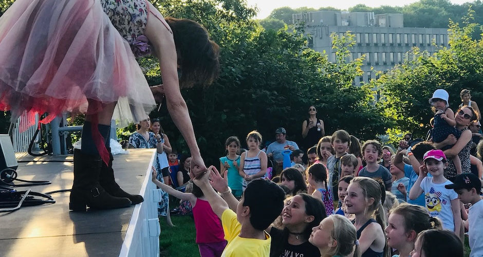 woman singing in tutu reaching for child's hand