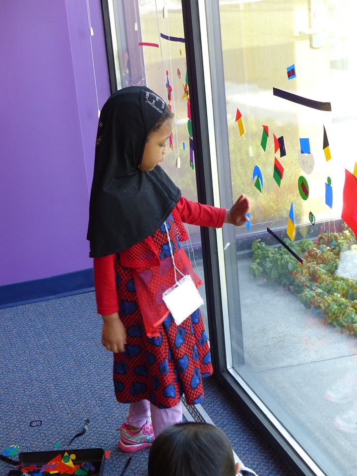 Children using color-form pieces on glass window