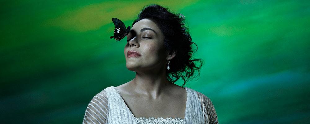 woman with butterfly on face standing with green backdrop