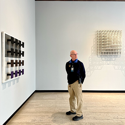 gallery guard looking off screen in art exhibit